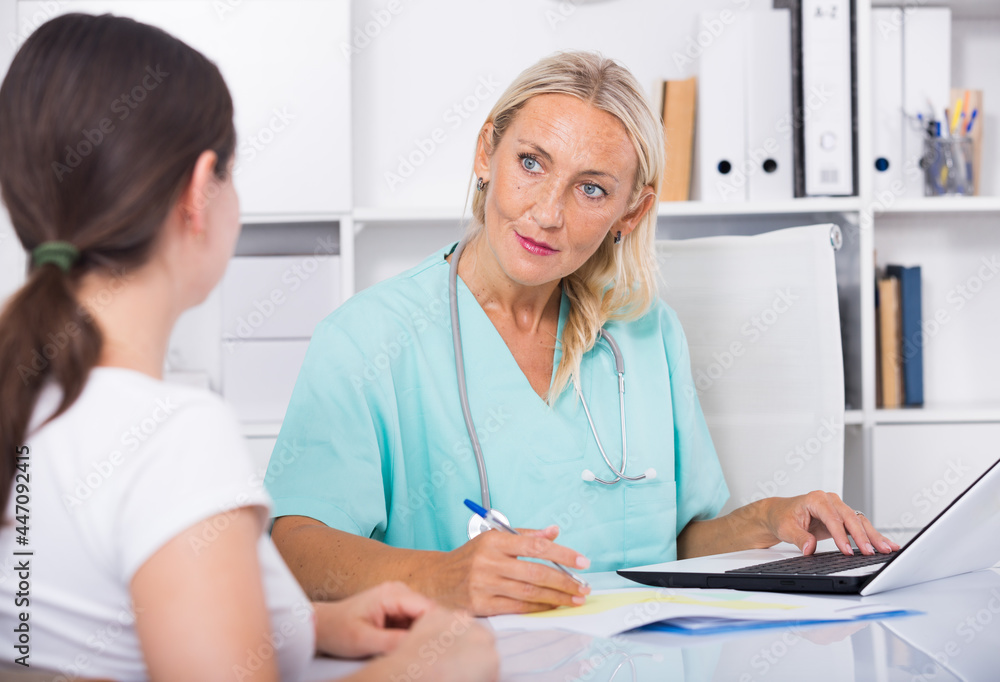 Fototapeta premium Portrait of mature female doctor listening to patient complaints at clinic