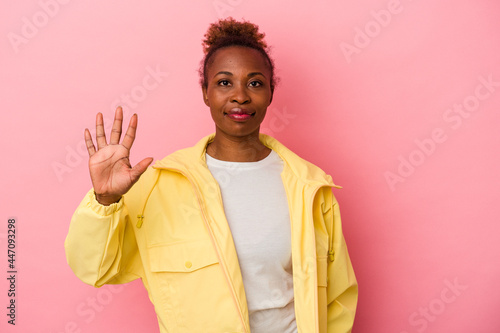 Young african american woman isolated on pink background smiling cheerful showing number five with fingers.