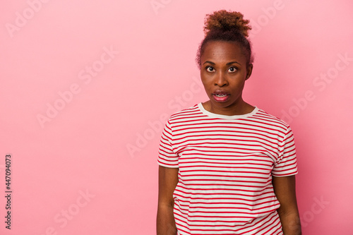 Young african american woman isolated on pink background being shocked because of something she has seen.