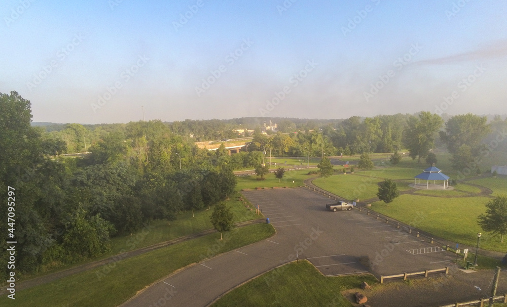 Overhead image of a municipal park in the summer on a foggy morning with a highway visible in the background