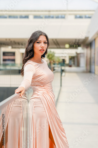 Portrait of a young girl in a shopping mall leaning on the handrail with a serious and seducing look on her face