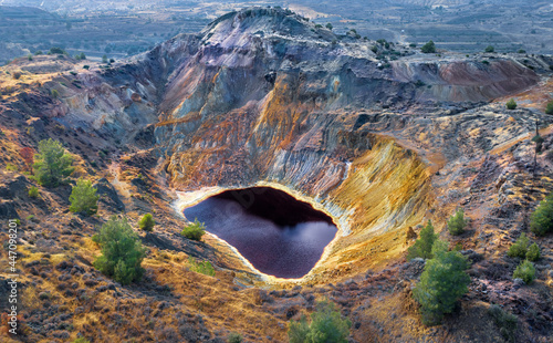 Acid red lake and colorful rocks in abandoned mine pit near Kampia, Cyprus. This area has large amounts of copper ore and sulfide deposits