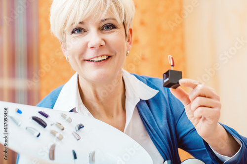 Older woman or female pensioner with a hearing problem make a hearing test and may need a hearing aid, she looking on a selection