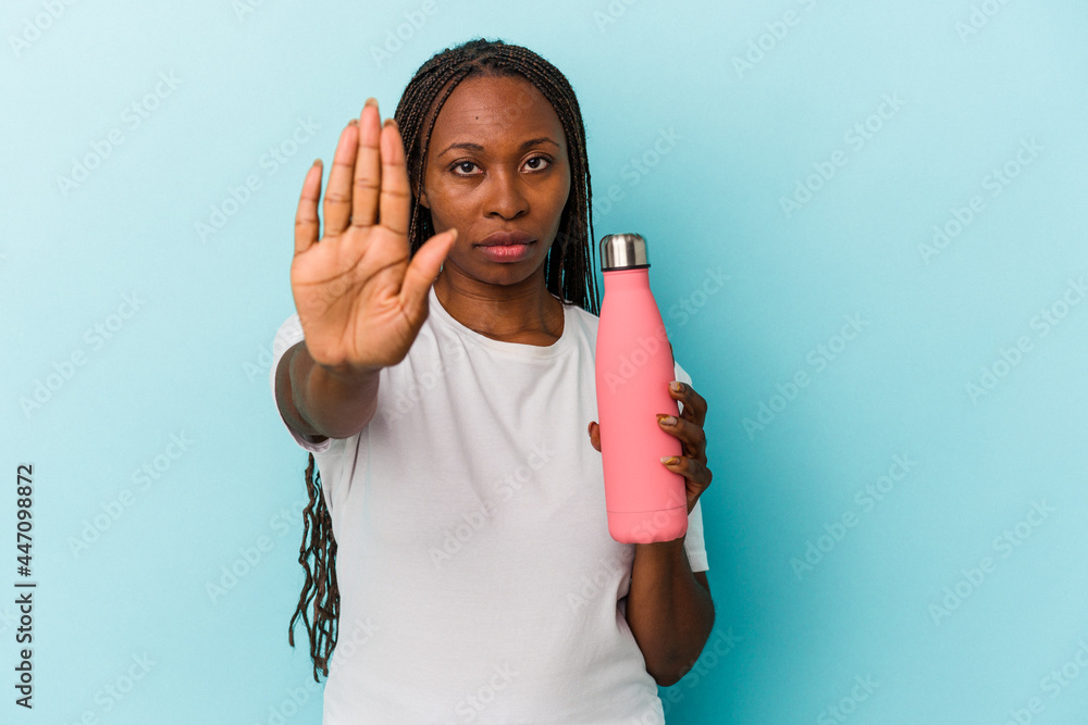 Young african american woman holding canteen isolated on blue background standing with outstretched hand showing stop sign, preventing you. Young african american woman holding canteen isolated on blue background standing with outstretched hand showing stop sign, preventing you.