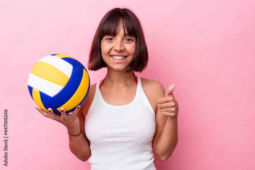 Young mixed race woman playing volleyball isolated on pink background smiling and raising thumb up Young mixed race woman playing volleyball isolated on pink background smiling and raising thumb up