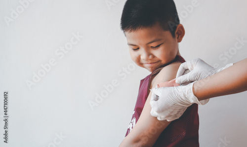 Fotografi Asian boy showing his arm after getting covid-19 vaccine.