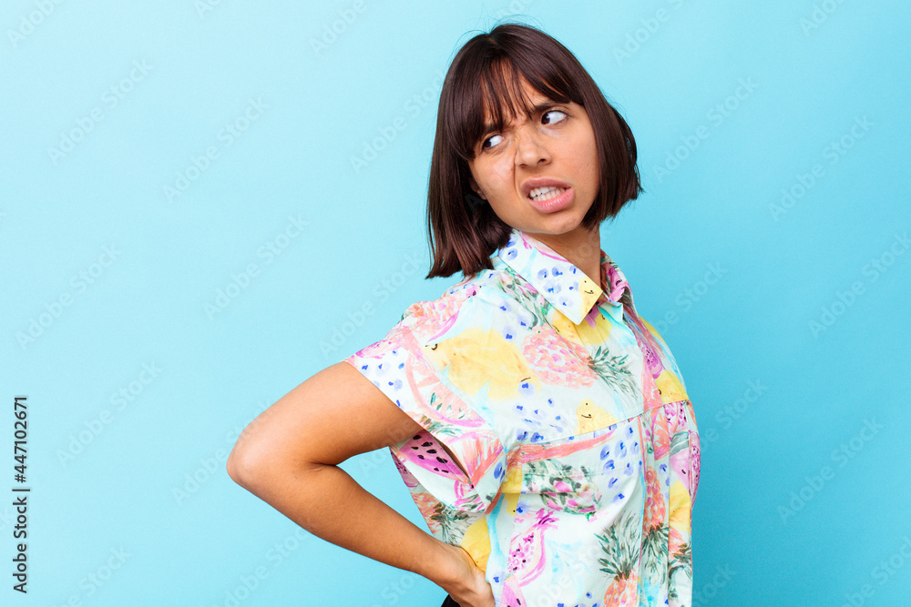 Young mixed race woman isolated on blue background suffering a back pain. Young mixed race woman isolated on blue background suffering a back pain.