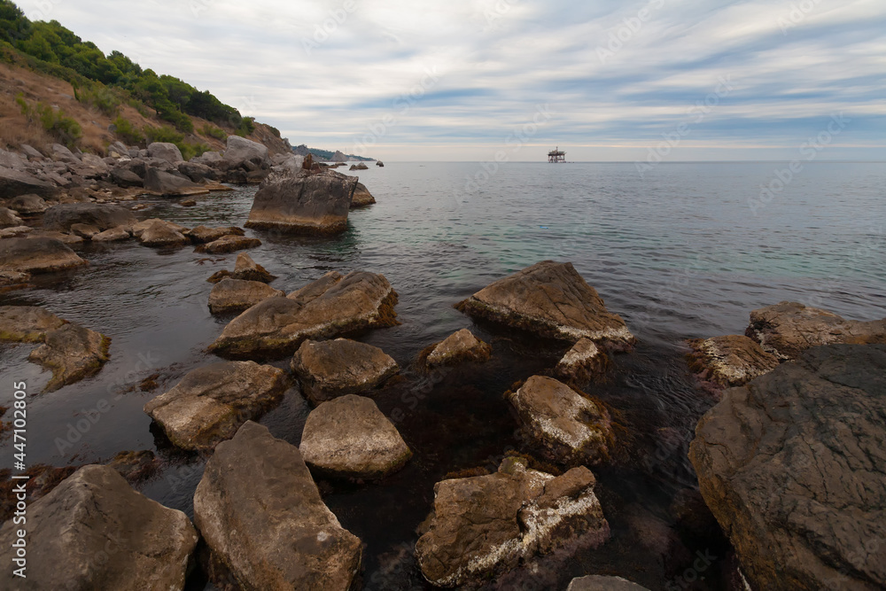 Black Sea, southern coast of Crimea. Quiet evening, calm sea. Large rocks in the salt water in the foreground.