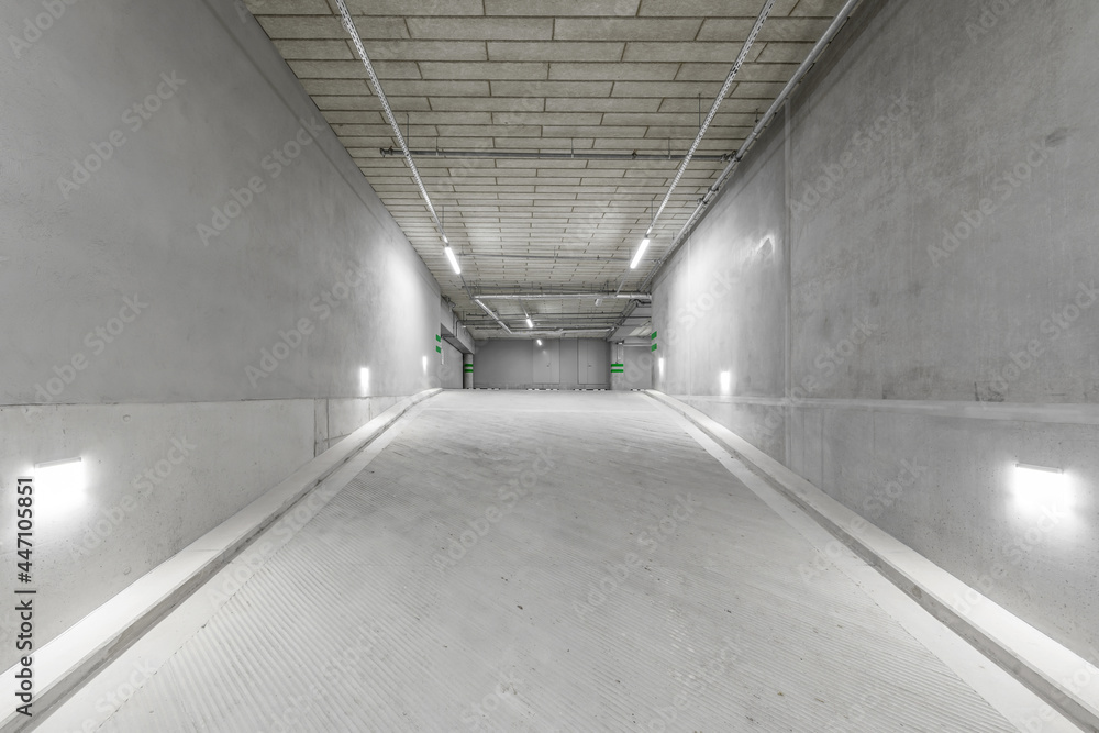 Empty public underground parking lot or garage interior with concrete stripe painted columns and signs