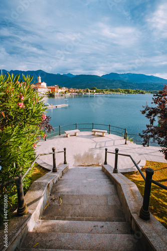 Fototapeta Naklejka Na Ścianę i Meble -  Feriolo, Verbania / Italy - June 2021: Feriolo village on Lake Maggiore with cloudy sky and steps to walk along the lake in the foreground