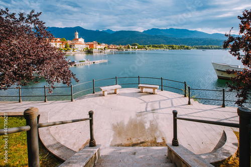 Fototapeta Naklejka Na Ścianę i Meble -  Feriolo, Verbania / Italy - June 2021: Feriolo village on Lake Maggiore with cloudy sky and steps to walk along the lake in the foreground