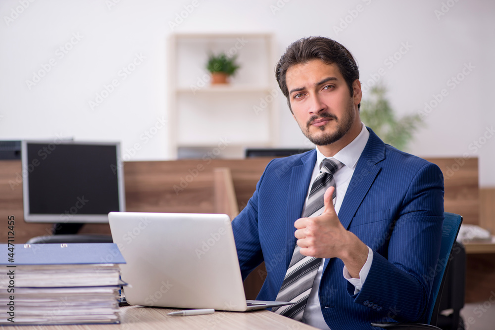 Young male employee and too much work in the office Young male employee and too much work in the office