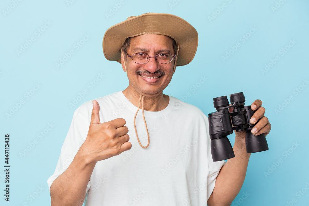 Middle aged indian fisherman holding rod isolated on blue background smiling and raising thumb up Middle aged indian fisherman holding rod isolated on blue background smiling and raising thumb up