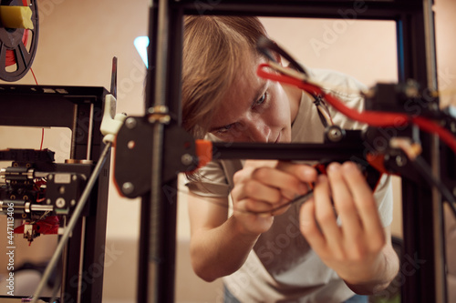 Young man repairing 3D printer