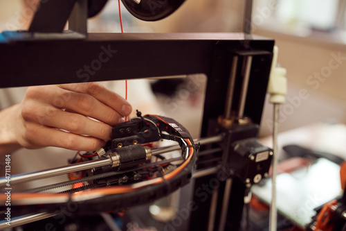 Crop man inserting plastic coil into 3D printer