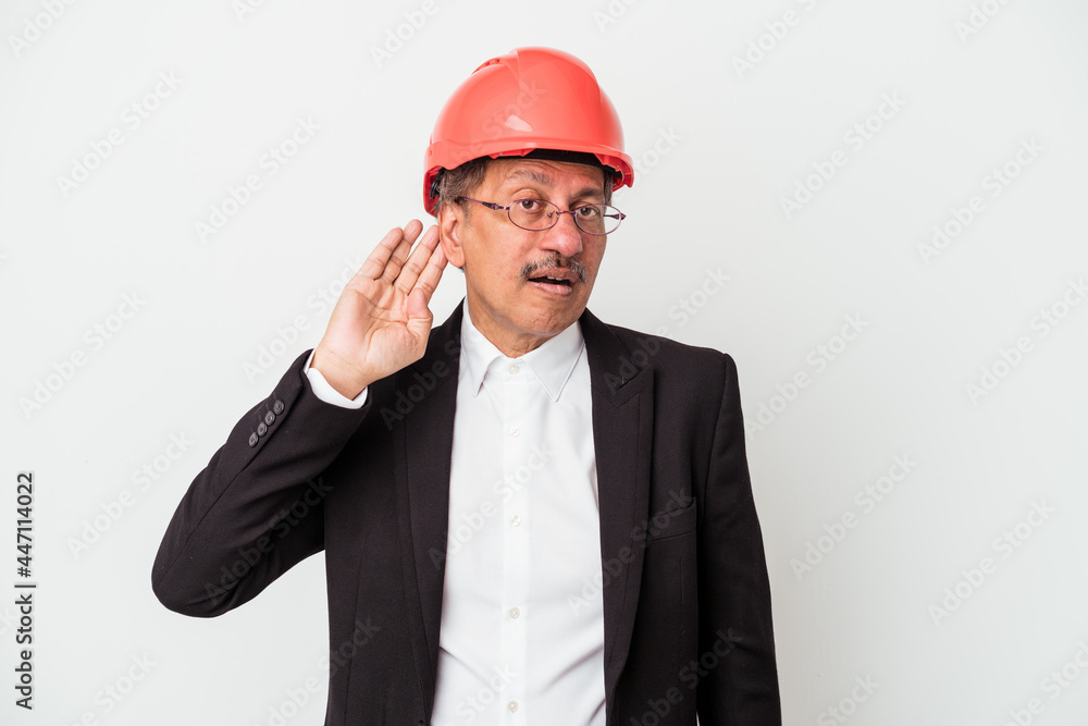 Middle aged indian architect man isolated on white background trying to listening a gossip. Middle aged indian architect man isolated on white background trying to listening a gossip.