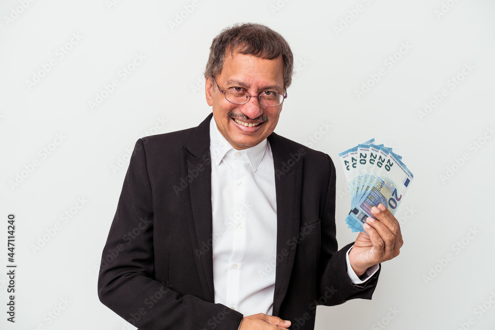 Middle aged indian business man holding bills isolated on white background laughing and having fun. Middle aged indian business man holding bills isolated on white background laughing and having fun.