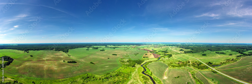 Panorama from height to winding river and summer fields with bushes and trees. Flight over the countryside