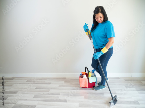 Bild auf Leinwand Caucasian young woman cleaning with a bottle of water brush and broom her house