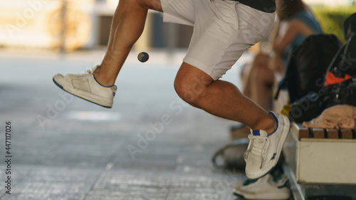 A young athlete fulfills its footbag tricks. Footbag freestyler practices on the Moscow city street. Game with small ball is very popular among youth. Active healthy lifestyle concept. photo