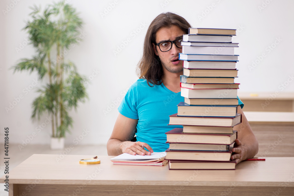 Young male student and a lot of books in the class Young male student and a lot of books in the class