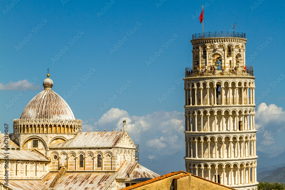 The leaning Tower of Pisa across the rooftops with the mountains in the distance