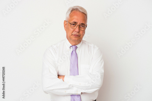 Senior american man isolated on white background frowning face in displeasure, keeps arms folded. © Asier