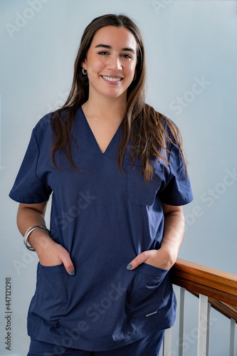 Female doctor at work with hands in his pockets in dark blue uniform standing in hallway