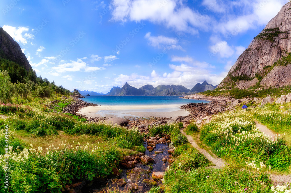 The concept of outdoor recreation. Beautiful landscape with a lonely tent near the sandy beach hidden between high mountains among blooming flowers and a clean stream on the shore of the blue bay.