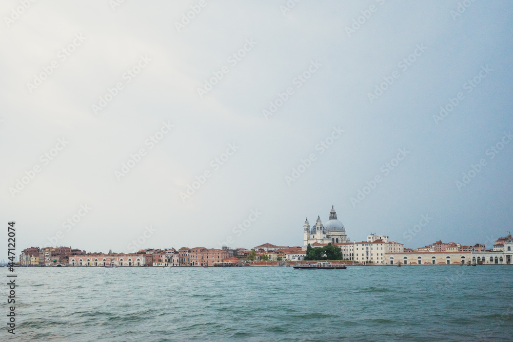 Basilica of Santa Maria della Salute and island of Venice under cloudy sky over water, Venice, Italy