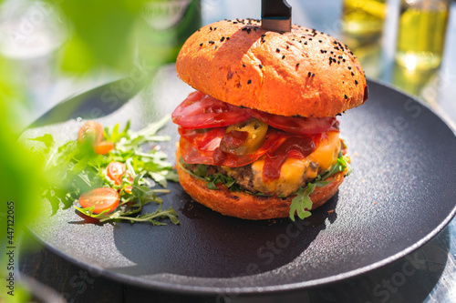 Burger with beef and vegetables, vegetable salad. Fast food.
The cook cooks and serves an appetizing dish. The finished dish served on a plate. Serving proposal, culinary photography. photo