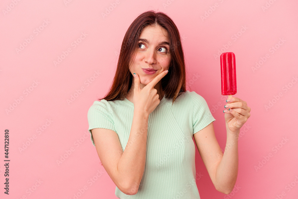 Young caucasian woman holding an ice cream isolated on blue background looking sideways with doubtful and skeptical expression. Young caucasian woman holding an ice cream isolated on blue background looking sideways with doubtful and skeptical expression.