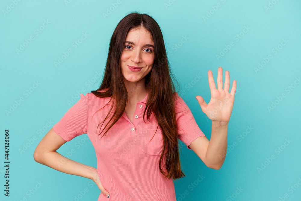 Young caucasian woman isolated on blue background smiling cheerful showing number five with fingers. Young caucasian woman isolated on blue background smiling cheerful showing number five with fingers.