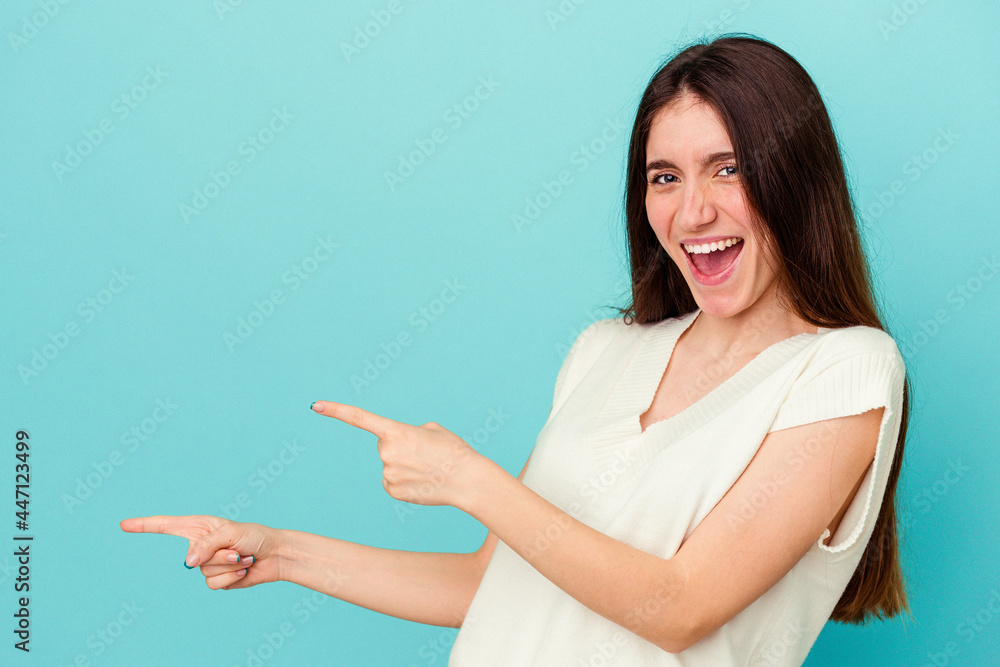 Young caucasian woman isolated on blue background pointing with forefingers to a copy space, expressing excitement and desire. Young caucasian woman isolated on blue background pointing with forefingers to a copy space, expressing excitement and desire.