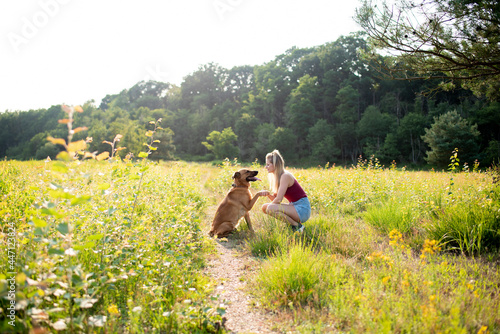 junge blonde Frau mir Schäferhund Mischling in der Natur beim Training und Spielen