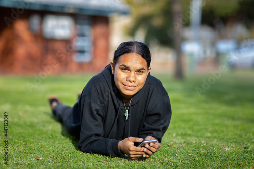 teenager lying on grass with mobile phone in hands photo