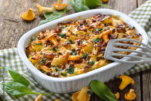 Nudelauflauf mit frischen Pfifferlingen und Blattspinat heiß aus dem Backofen serviert – Chanterelle pasta casserole with spinach leaves and cheese served hot from the oven