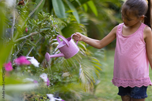 little girl in pink water flowers with pink watering can photo