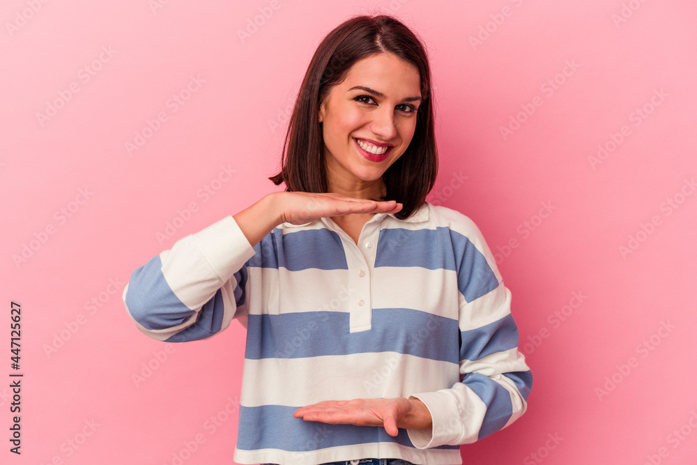 Young caucasian woman isolated on pink background holding something with both hands, product presentation. Young caucasian woman isolated on pink background holding something with both hands, product presentation.