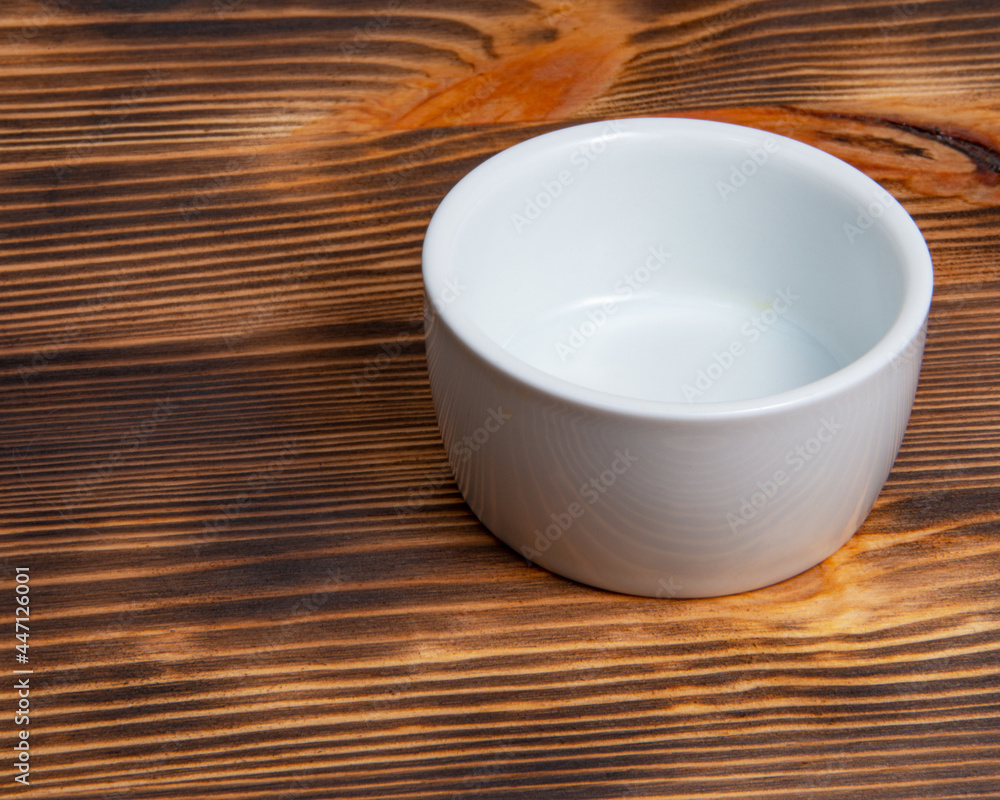 Empty white dish on dark wooden desk Empty white dish on dark wooden desk