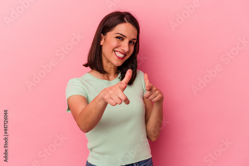 Young caucasian woman isolated on pink background pointing to front with fingers.