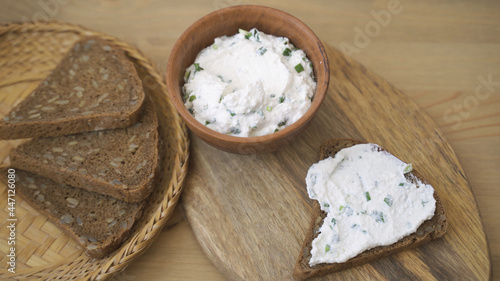 Spreading cream cheese with scallions on bread. Smear soft cheese on bread.