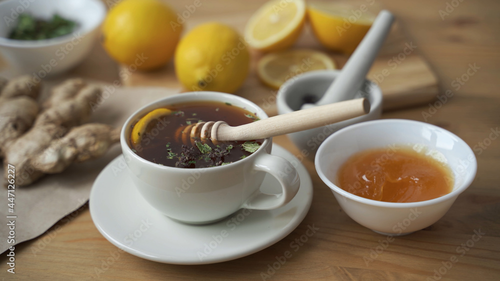 Put a teaspoon of honey in a Cup of hot tea with lemon. Close up. Put a teaspoon of honey in a Cup of hot tea with lemon. Close up.