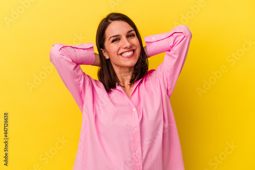 Young caucasian woman isolated on yellow background feeling confident, with hands behind the head.