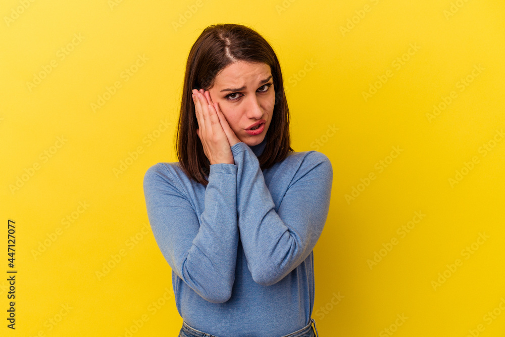 Young caucasian woman isolated on yellow background yawning showing a tired gesture covering mouth with hand. Young caucasian woman isolated on yellow background yawning showing a tired gesture covering mouth with hand.