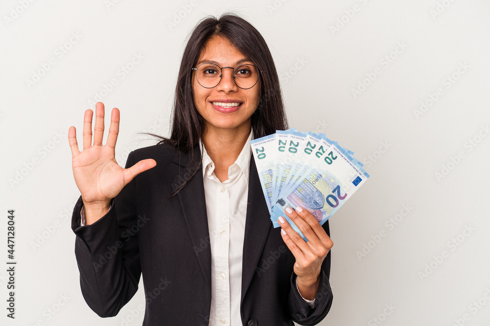Young business latin woman holding bills isolated on white background smiling cheerful showing number five with fingers. Young business latin woman holding bills isolated on white background smiling cheerful showing number five with fingers.