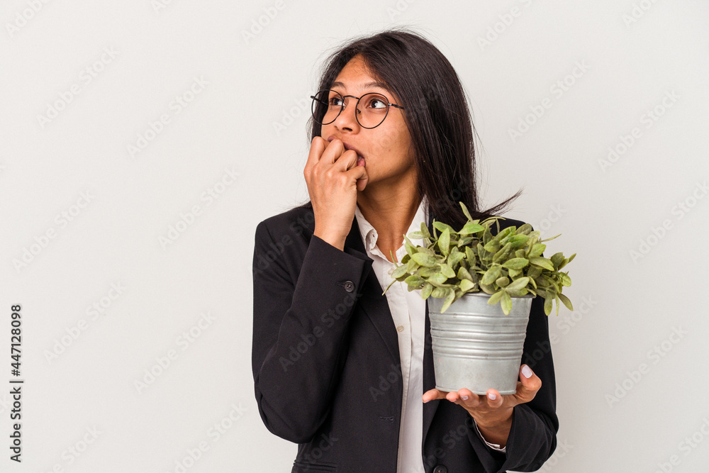 Young business latin woman holding plants isolated on white background relaxed thinking about something looking at a copy space. Young business latin woman holding plants isolated on white background relaxed thinking about something looking at a copy space.