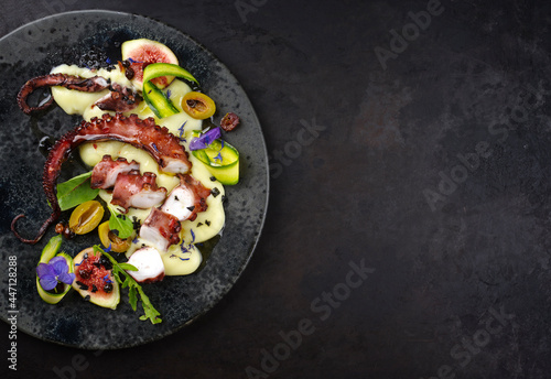 Modern style Italian polpo alla griglia su crema di patate with barbecued octopus, potato creme and fresh fruits as top view on a Nordic design plate with copy space right