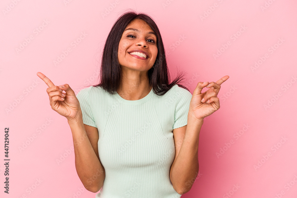 Young latin woman isolated on pink background pointing to different copy spaces, choosing one of them, showing with finger. Young latin woman isolated on pink background pointing to different copy spaces, choosing one of them, showing with finger.