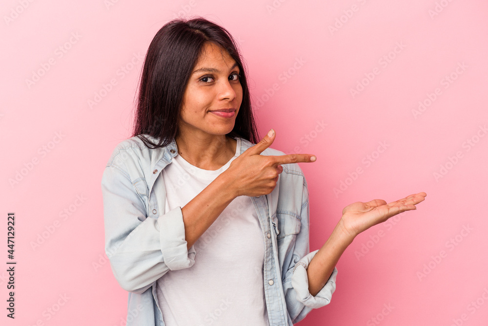 Young latin woman isolated on pink background excited holding a copy space on palm. Young latin woman isolated on pink background excited holding a copy space on palm.